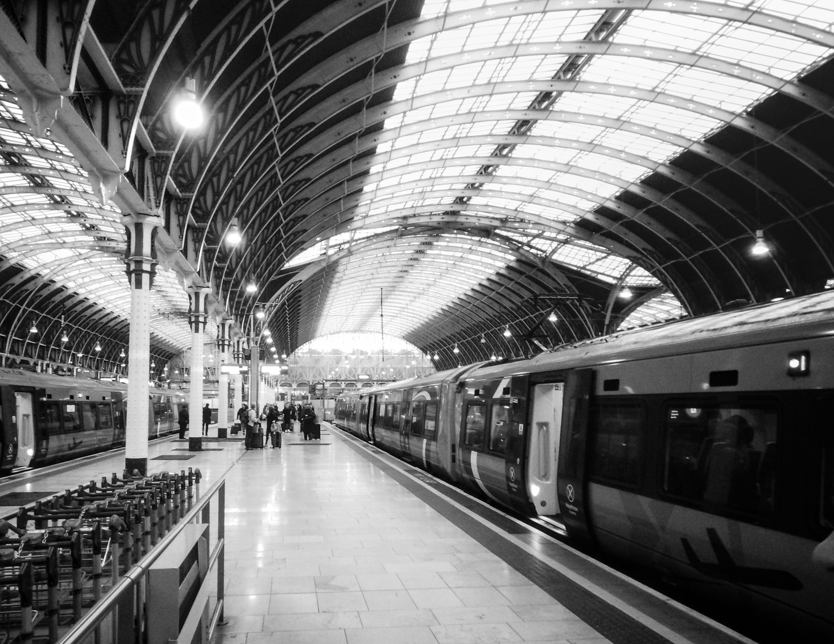 Timeless view of a busy railway station platform with trains and commuters.